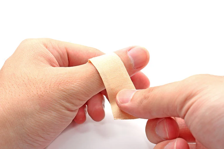 person applying bandaid on his wound