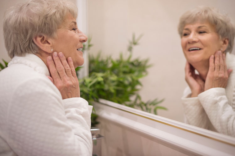 an elder woman looking into a mirror and getting ready